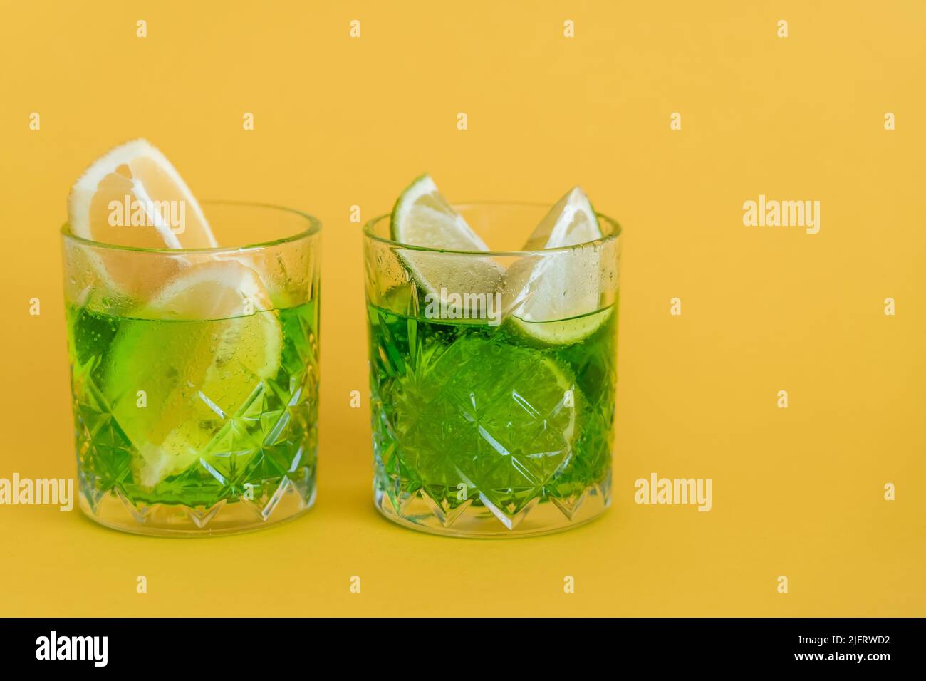 sliced citrus fruits in glasses with sparkling mojito drink on yellow Stock Photo