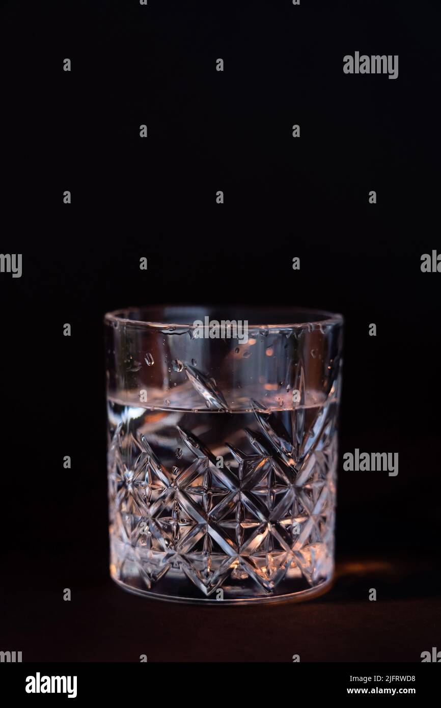 cool faceted glass with rum isolated on black Stock Photo