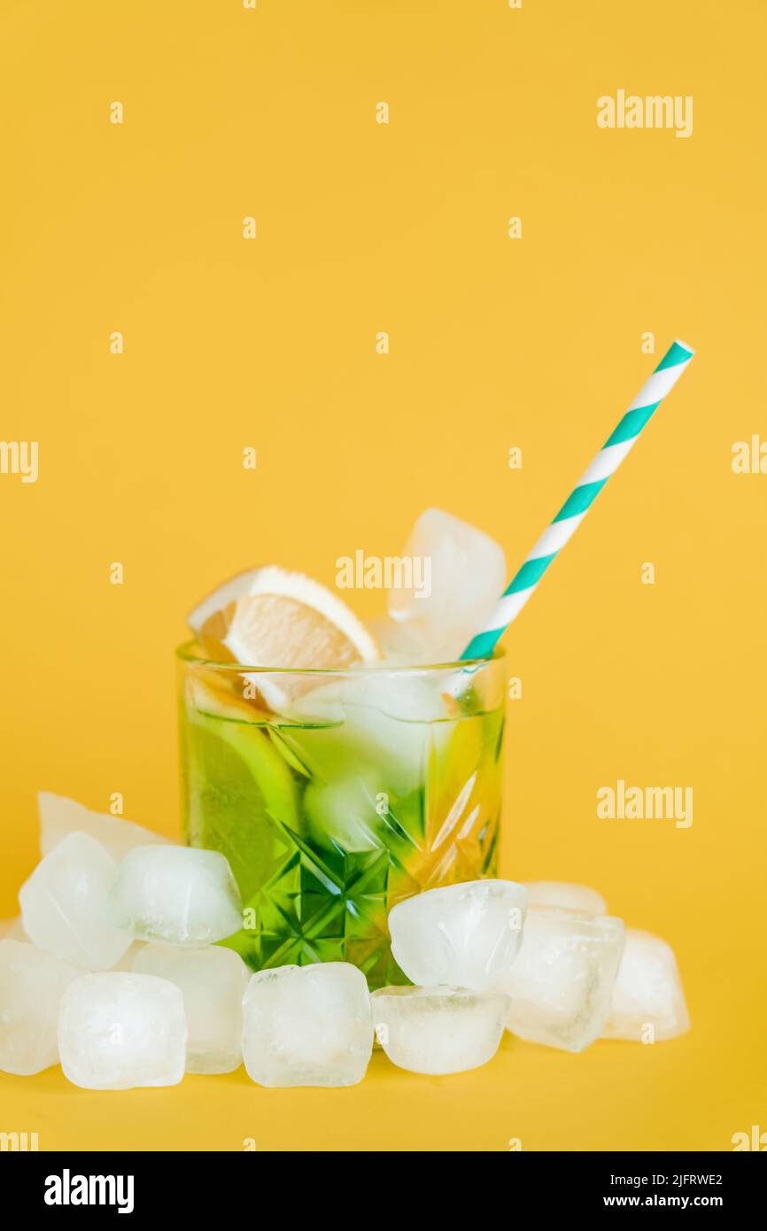 ice cubes and sliced lemons in glass with mojito drink on yellow Stock Photo