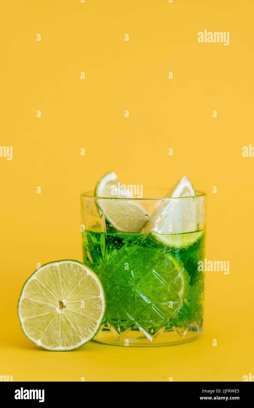 sliced limes in glass with sparkling mojito drink on yellow Stock Photo