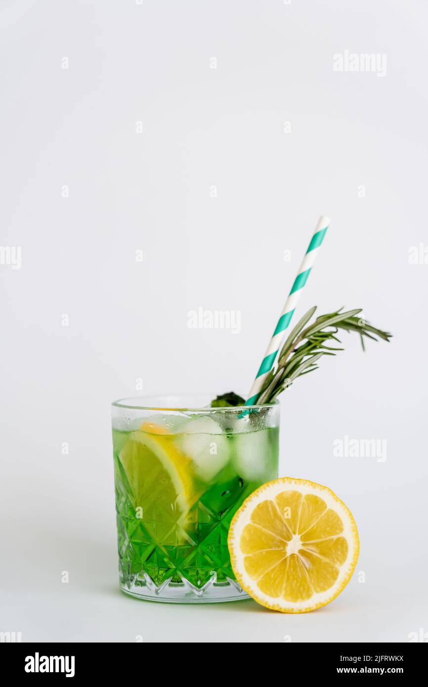 cool faceted glass with lemon mojito, ice cubes and rosemary on white Stock Photo