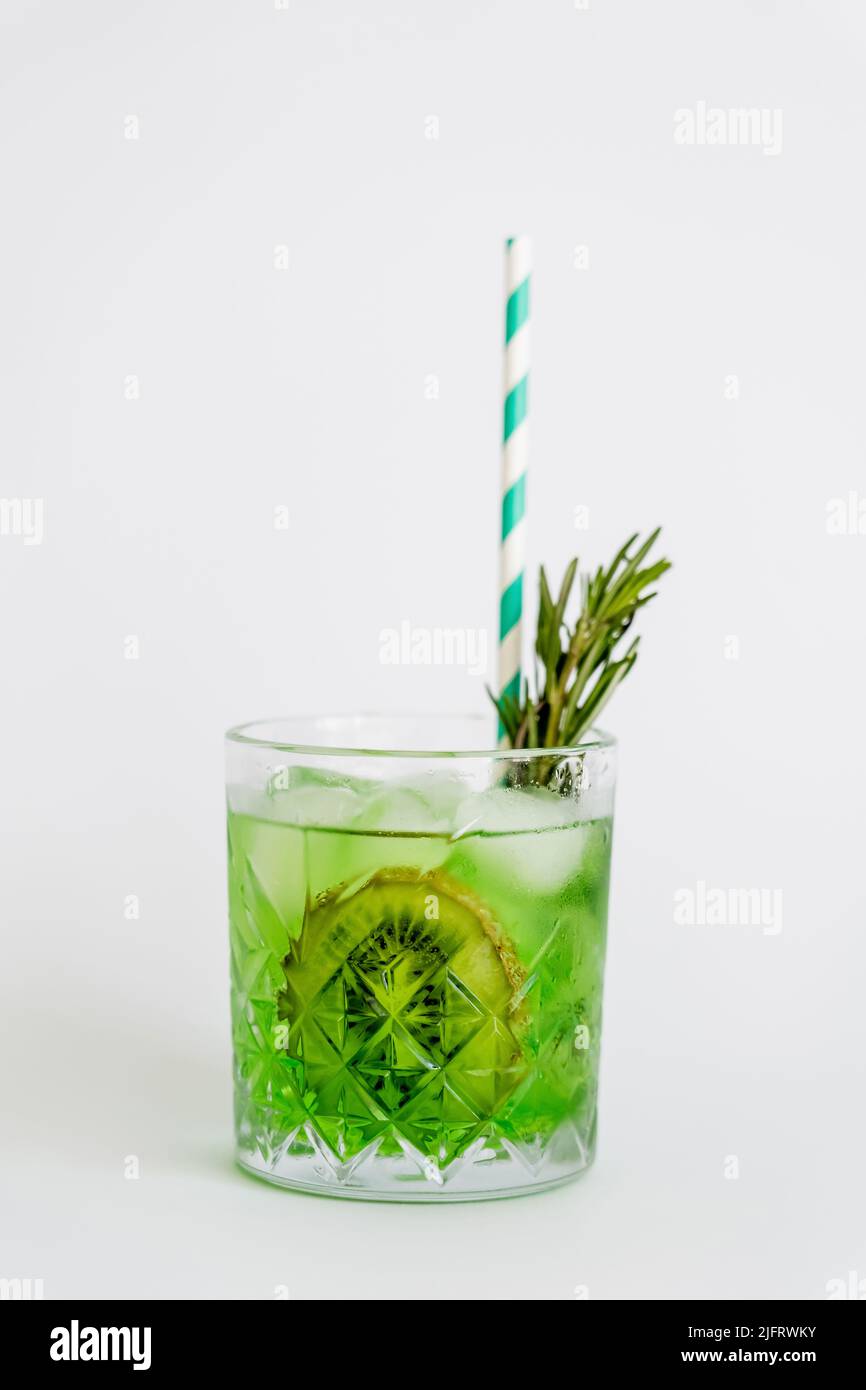 cool faceted glass with kiwi mojito, ice cubes and rosemary isolated on white Stock Photo
