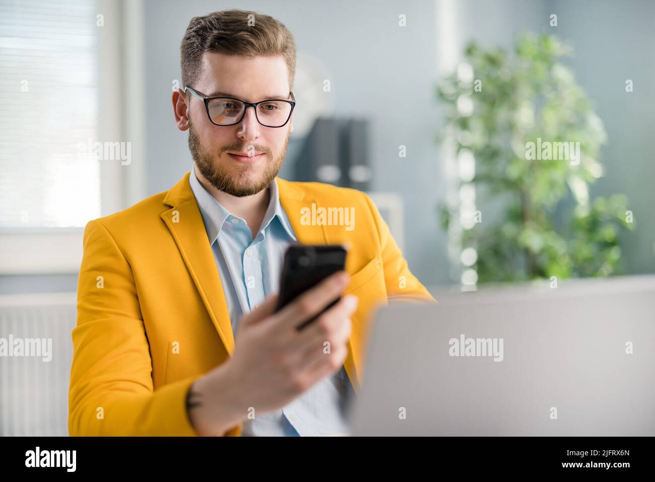 Male sitting at workplace with smartphone Stock Photo