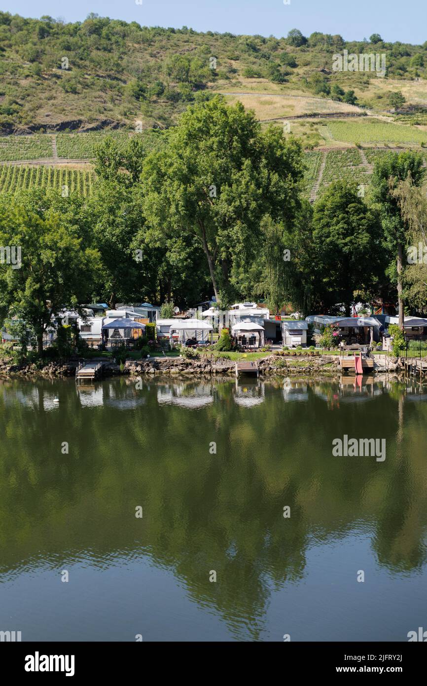 Camping, wild camping in tents and caravans on the banks of the River Rhine in Germany. Tents are reflected in the water. Stock Photo