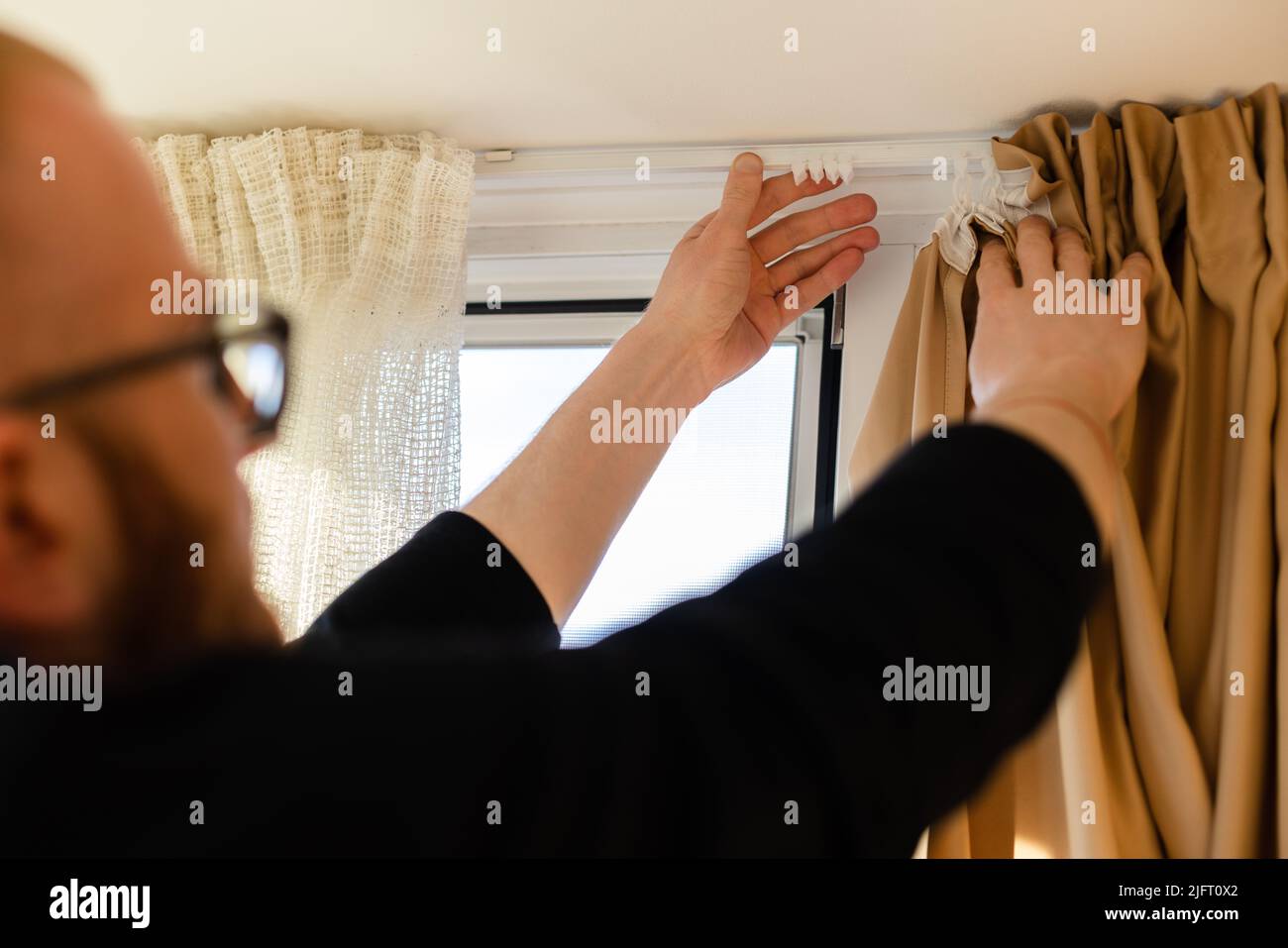 Man hanging curtains on the plastic hooks Stock Photo - Alamy