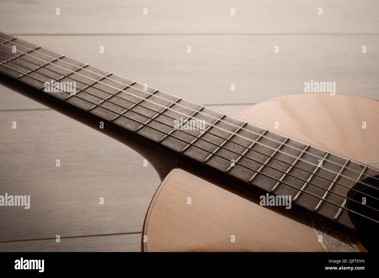 Classical guitar body and fretboard close up, on a light wood
