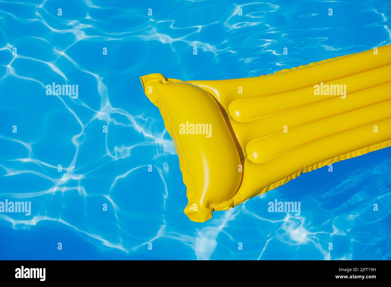 A yellow air mattress floats in an empty pool of blue water. Summer holiday concept Stock Photo