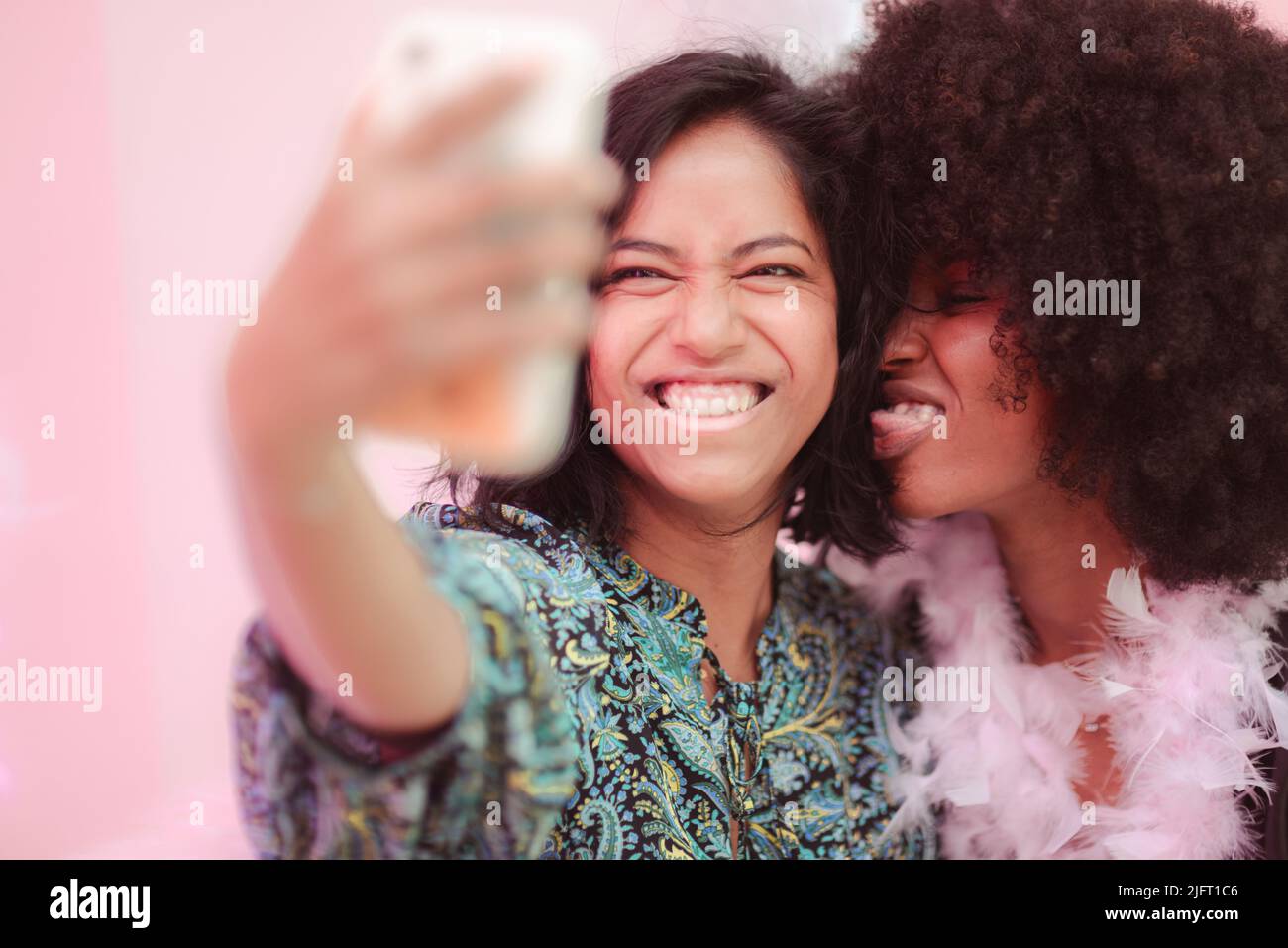 Couple of young south asian woman and african amercian woman having fun taking selfies in a bar. Stock Photo