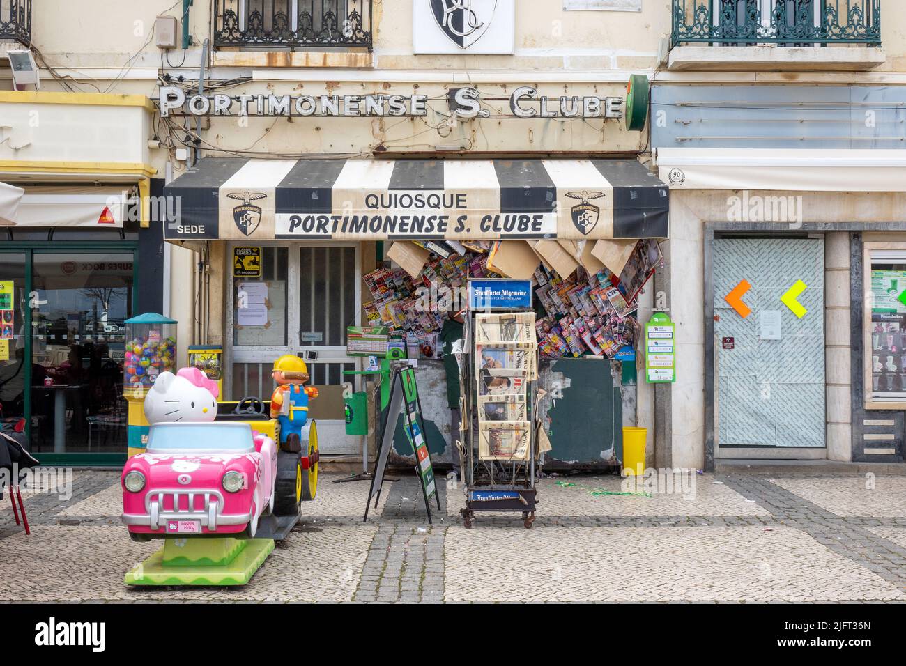 Newspaper Stand Kiosk In Front Of A Closed Down Shop Portimonense Sporting Clube In Portimao, Portugal Stock Photo