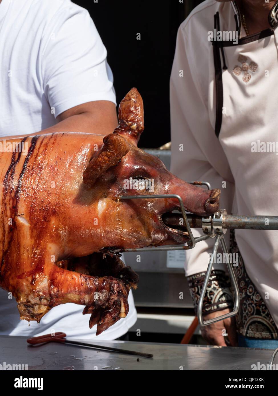 Vertical photo of a grilled suckling pig on a spit Stock Photo