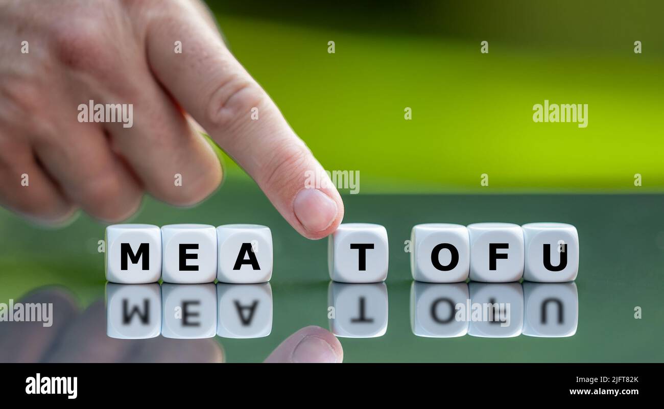 Hand moves dice and changes the word meat to tofu. Stock Photo