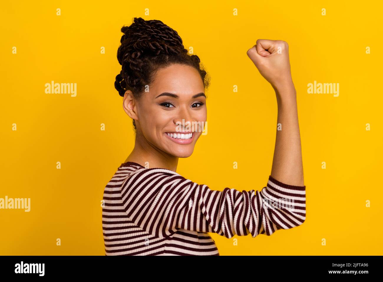 Profile photo of pretty satisfied girl toothy smile arm flexing biceps isolated on yellow color background Stock Photo