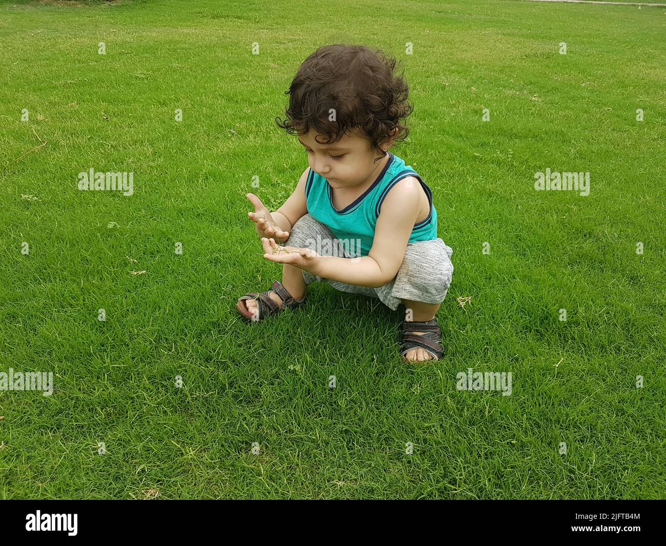 Cute little baby boy playing outdoor on a grass. Stock Photo