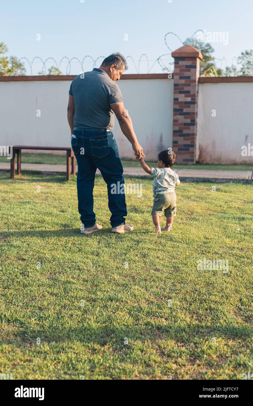 grandfather walking with grandson on his back in the park Stock Photo