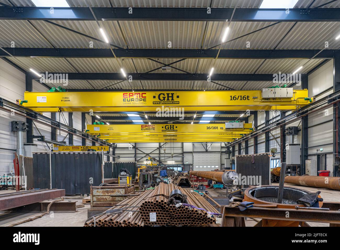 Interior of a steel factory with mobile cranes, steel piles and beams ...