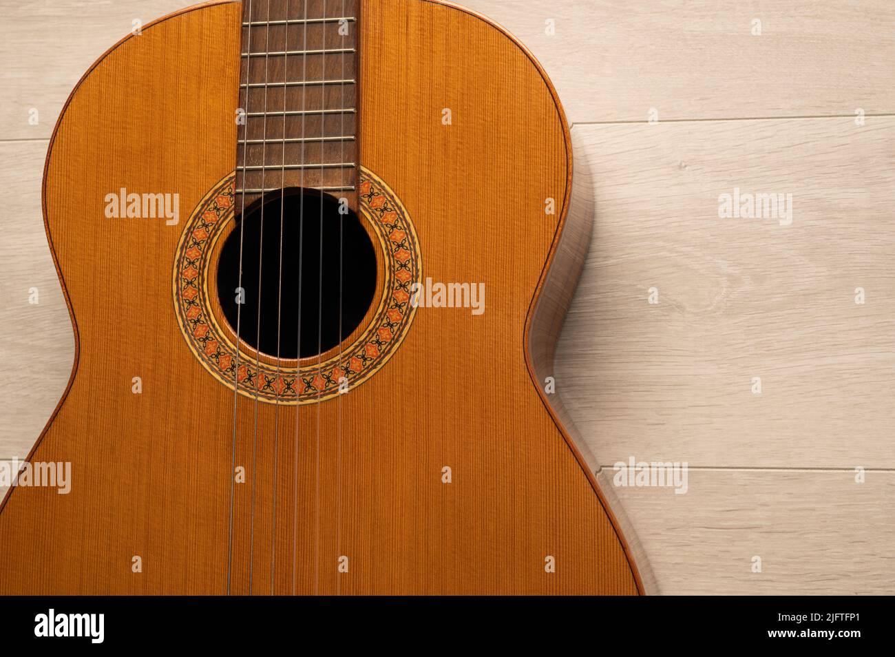 Classical guitar body close up, on a light wood background with copy
