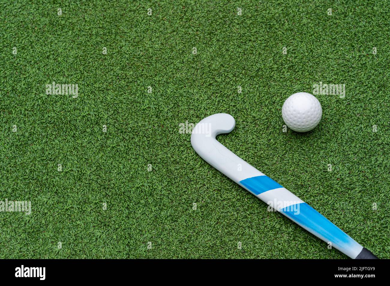 iField hockey stick and ball on green grass. Horizontal sport theme