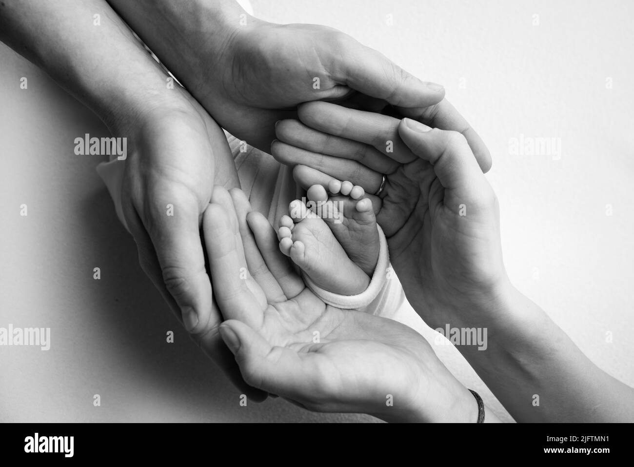 The palms of the father, the mother are holding the foot of the newborn