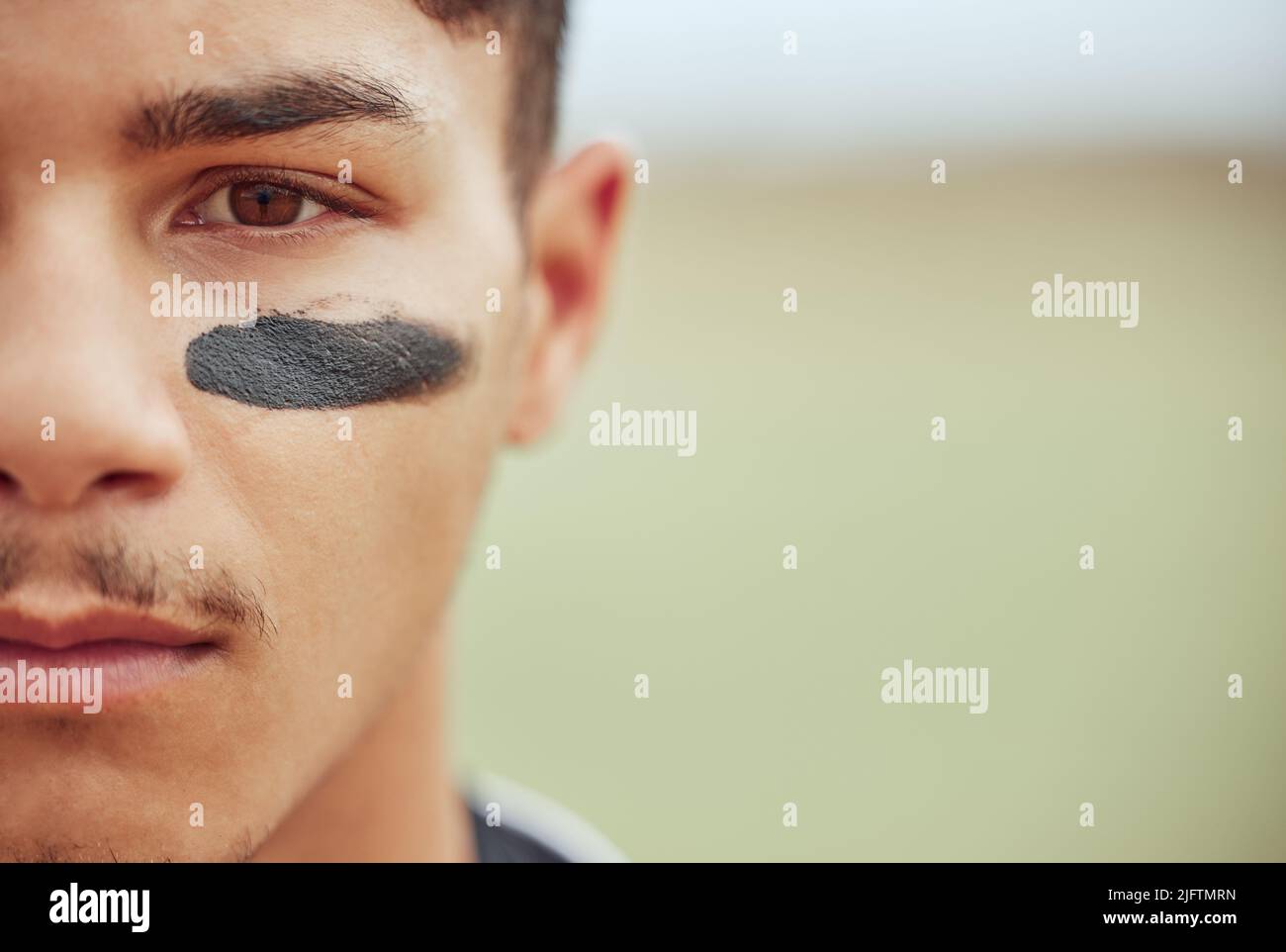Portrait of a young male baseball player standing on a field with black
