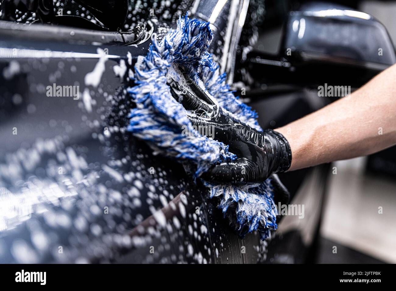 car wash employee thoroughly washes a modern ca Stock Photo