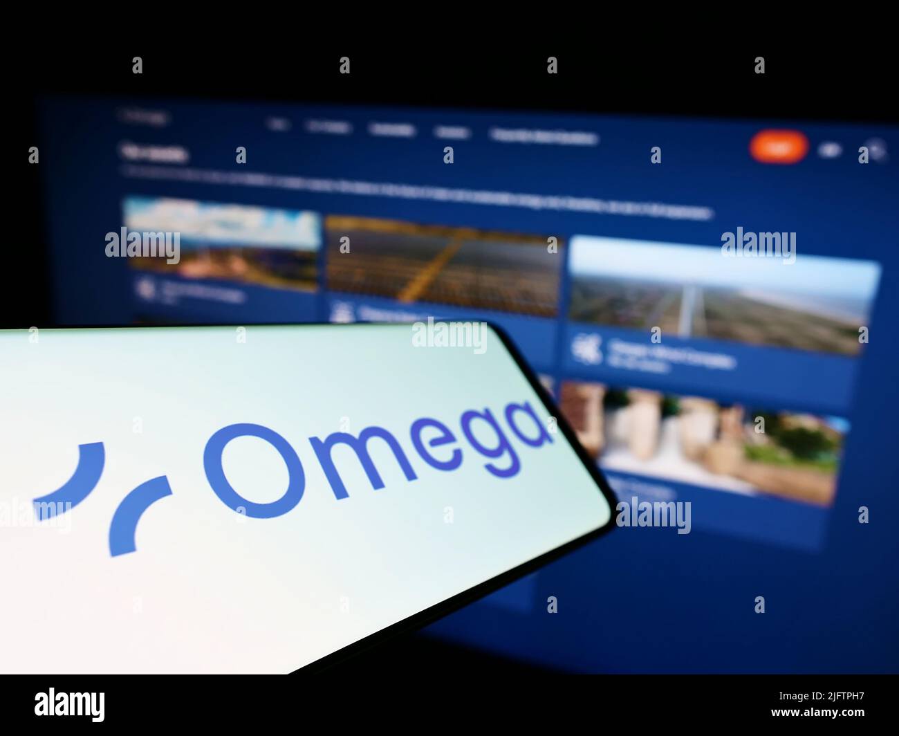 Cellphone with logo of Brazilian renewable energy company Omega Energia on screen in front of business website. Focus on left of phone display. Stock Photo