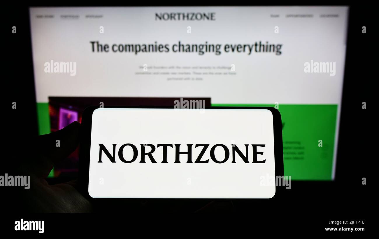 Person holding smartphone with logo of British venture capital company Northzone on screen in front of website. Focus on phone display. Stock Photo