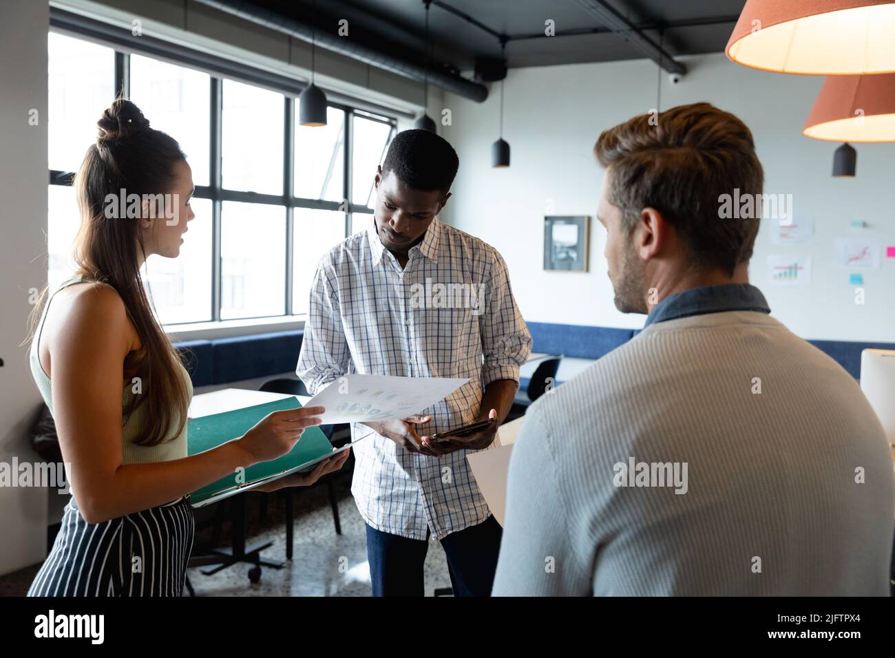 Multiracial colleagues discussing business plan over document in creative office Stock Photo