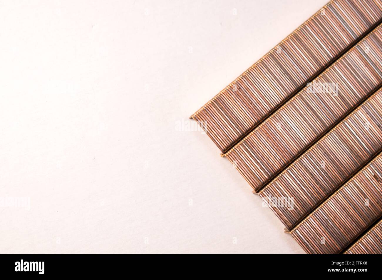 A top view of row of bronze stapler pins on white table with copy space ...