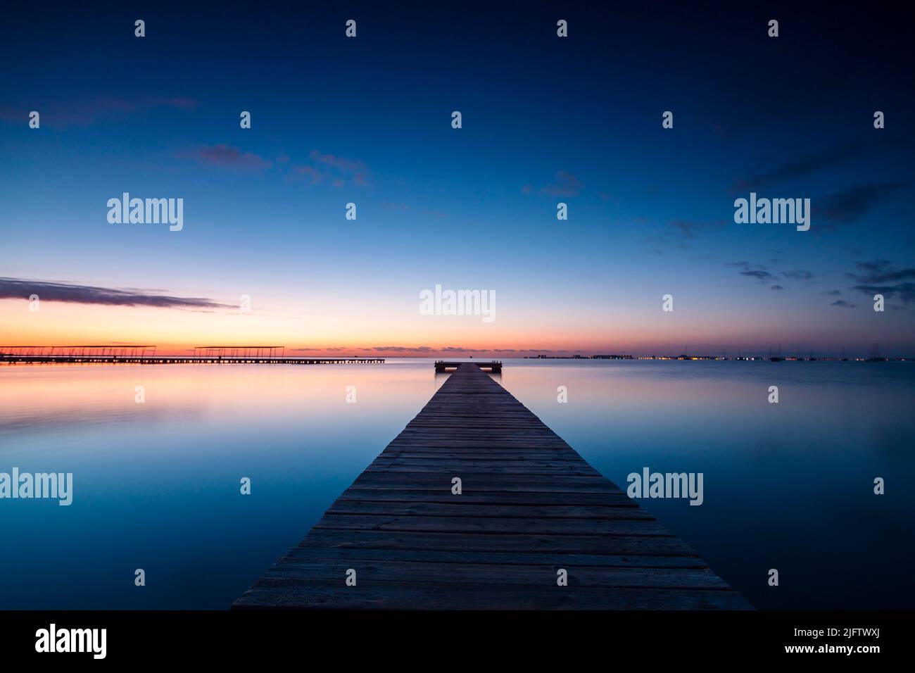 Horizontal photo of the sunrise and the calm waters of the Mar Menor, Region of Murcia, Spain, from a wooden jetty in San Javier Stock Photo