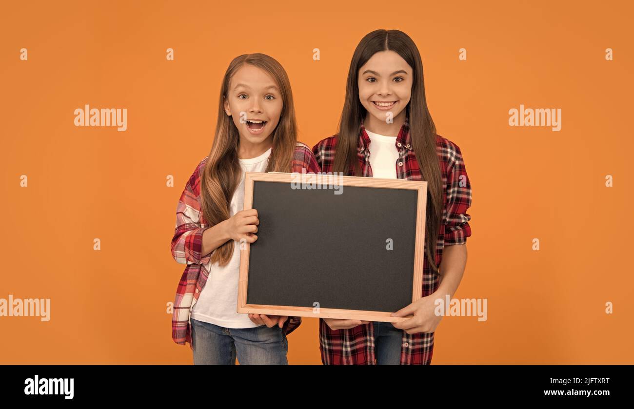 happy teen girls hold blackboard. children advertising. back to school. kids presenting information Stock Photo