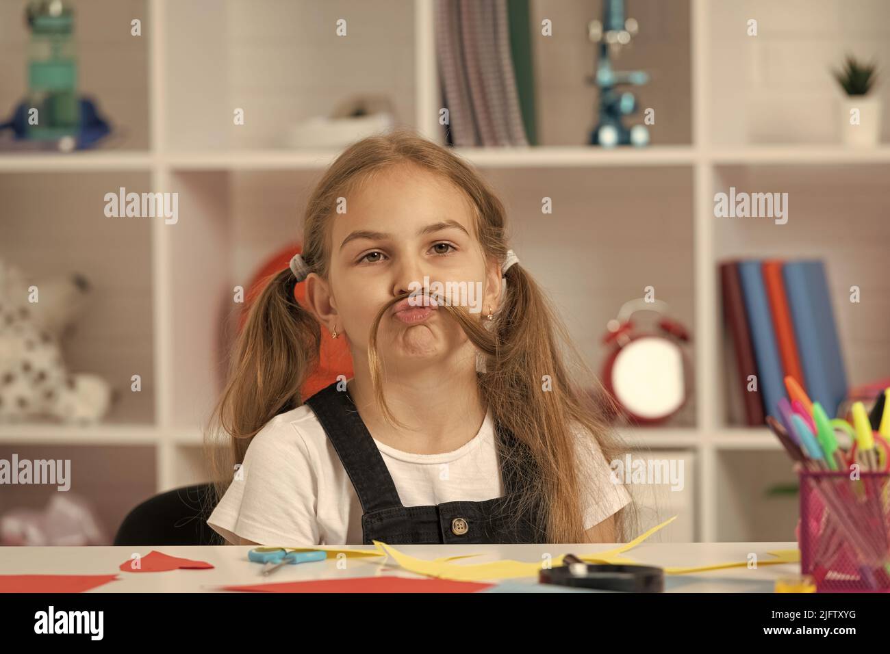 cute kid having fun with long hair pony tail at school lesson in classroom wear uniform, have fun Stock Photo