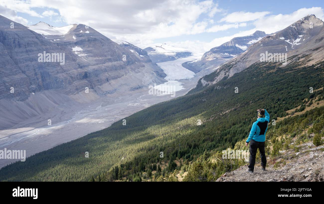 Male hiker enjoying the view on untouched alpine valley with glacier on its end, Jasper, Canada Stock Photo