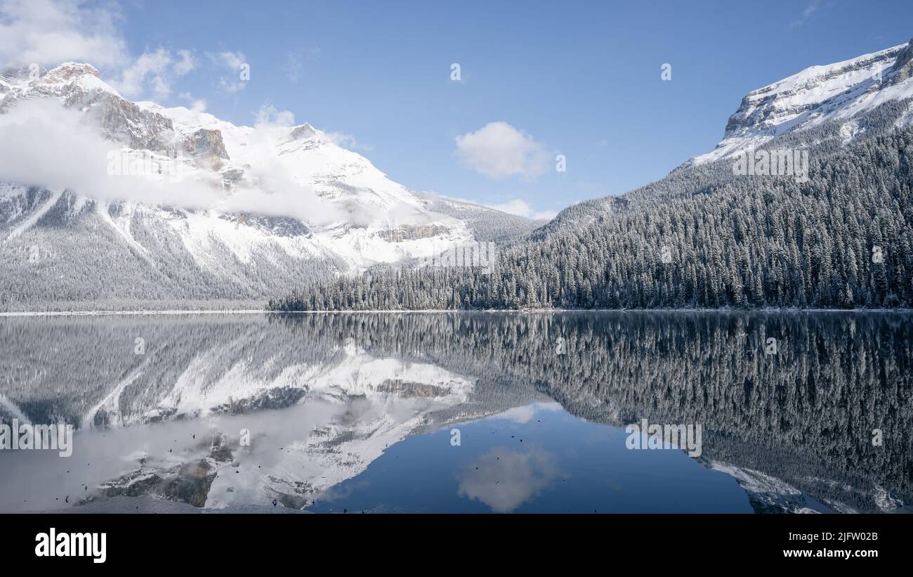 Still alpine lake reflecting its winter surroundings like a mirror, wide, Yoho N. Park, Canada Stock Photo