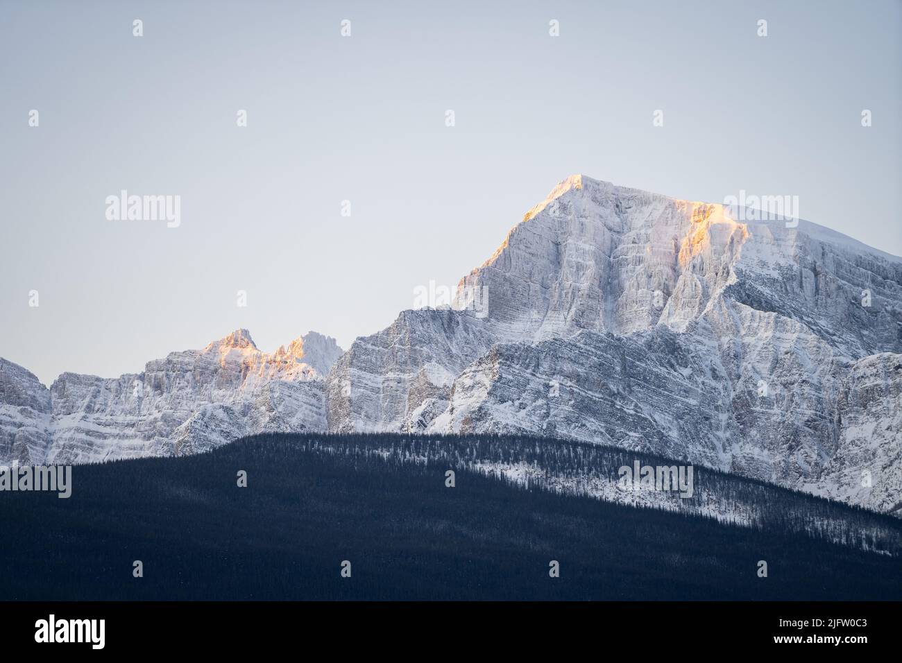 Rocky peak catching the first light on a cold winter morning, narrow shot, Banff N. Park, Canada Stock Photo