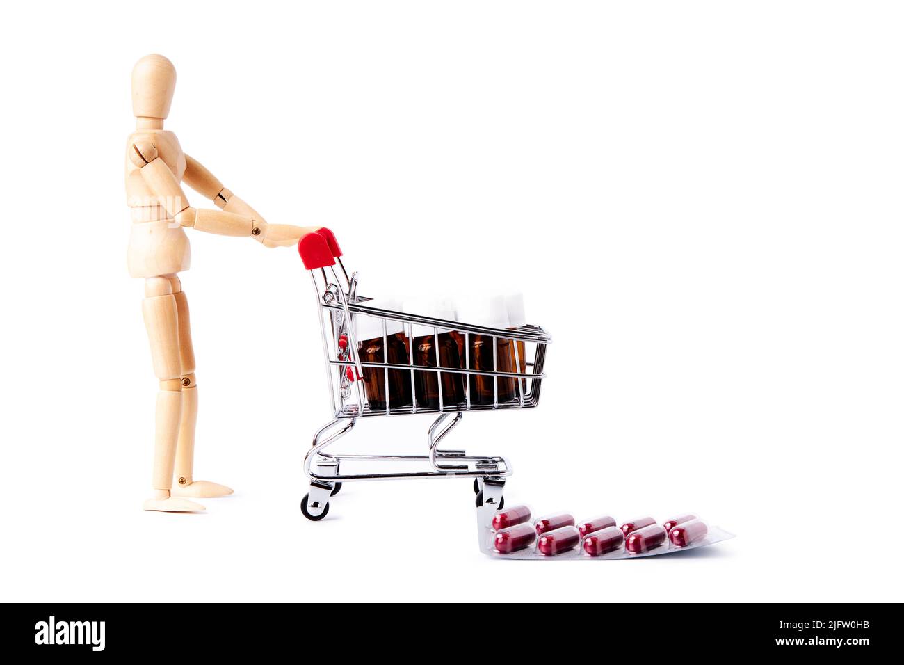 Dummy pushing shopping cart full of medicine jars and pills on the floor. Medicine and health concept Stock Photo