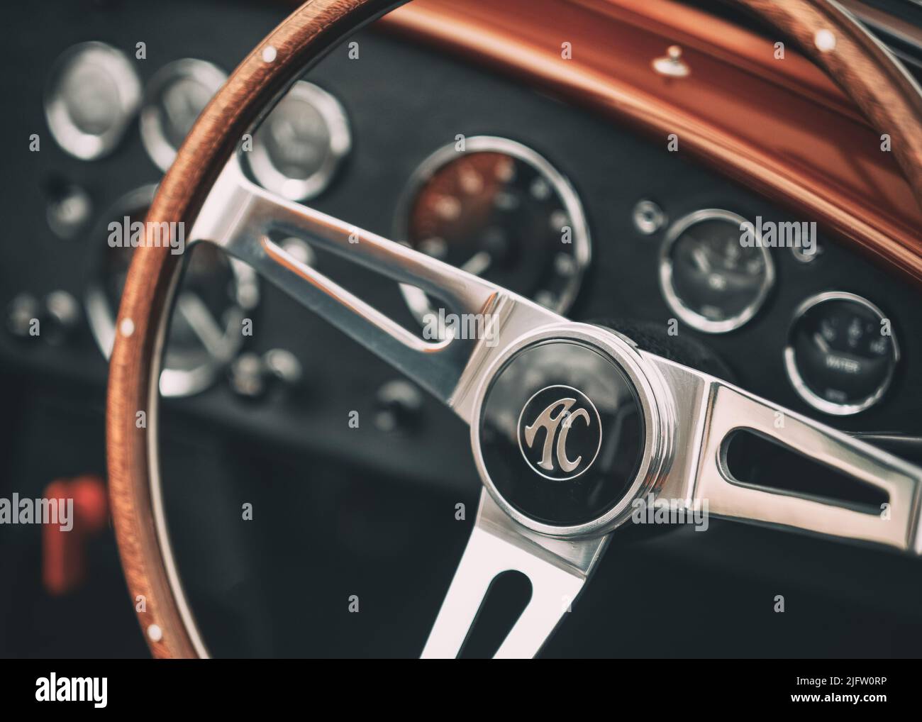The steering wheel and dashboard section of a red AC Cobra classic sports car Stock Photo