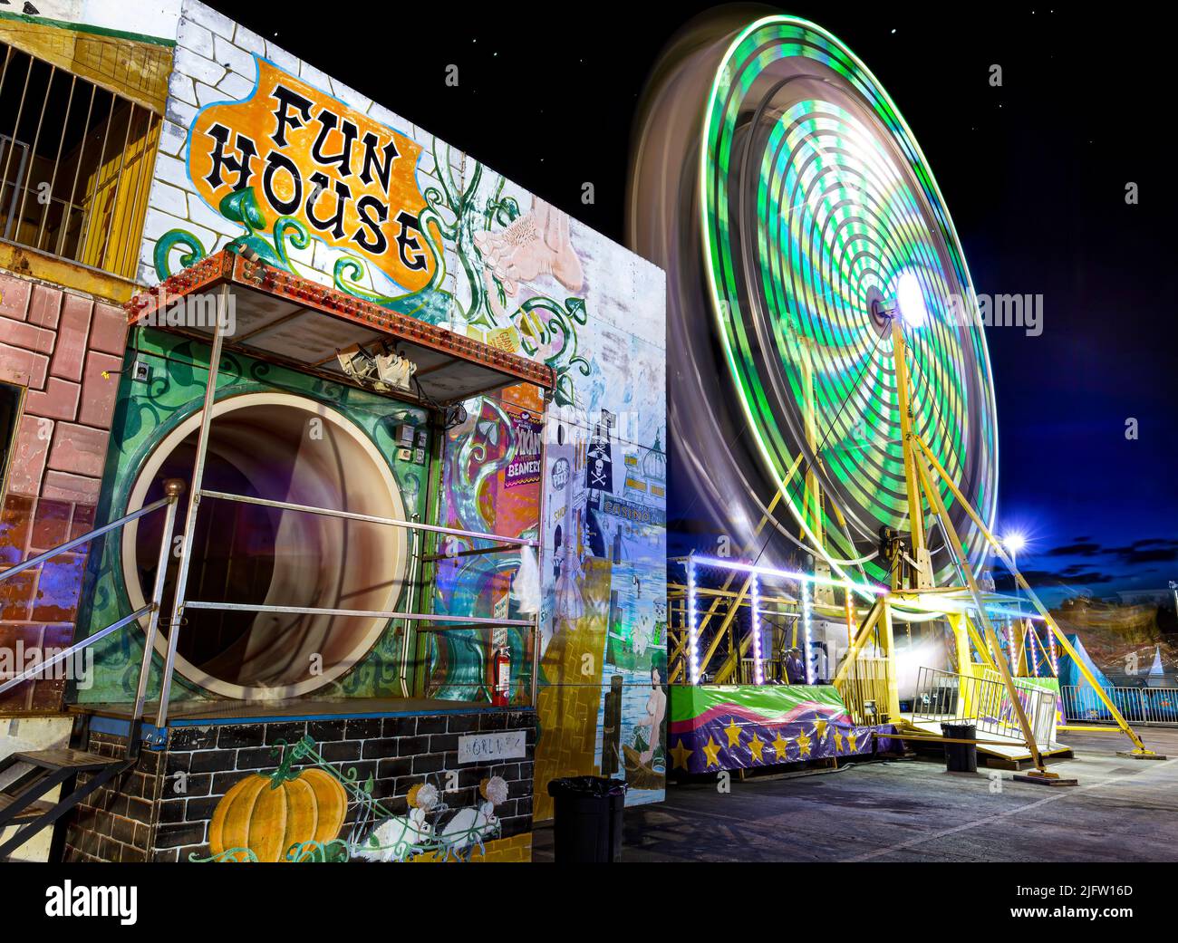 A ferris wheel spins next to a funhouse at the Broward County Fair at Gulfstream Park in Hallandale Beach, Florida. Stock Photo