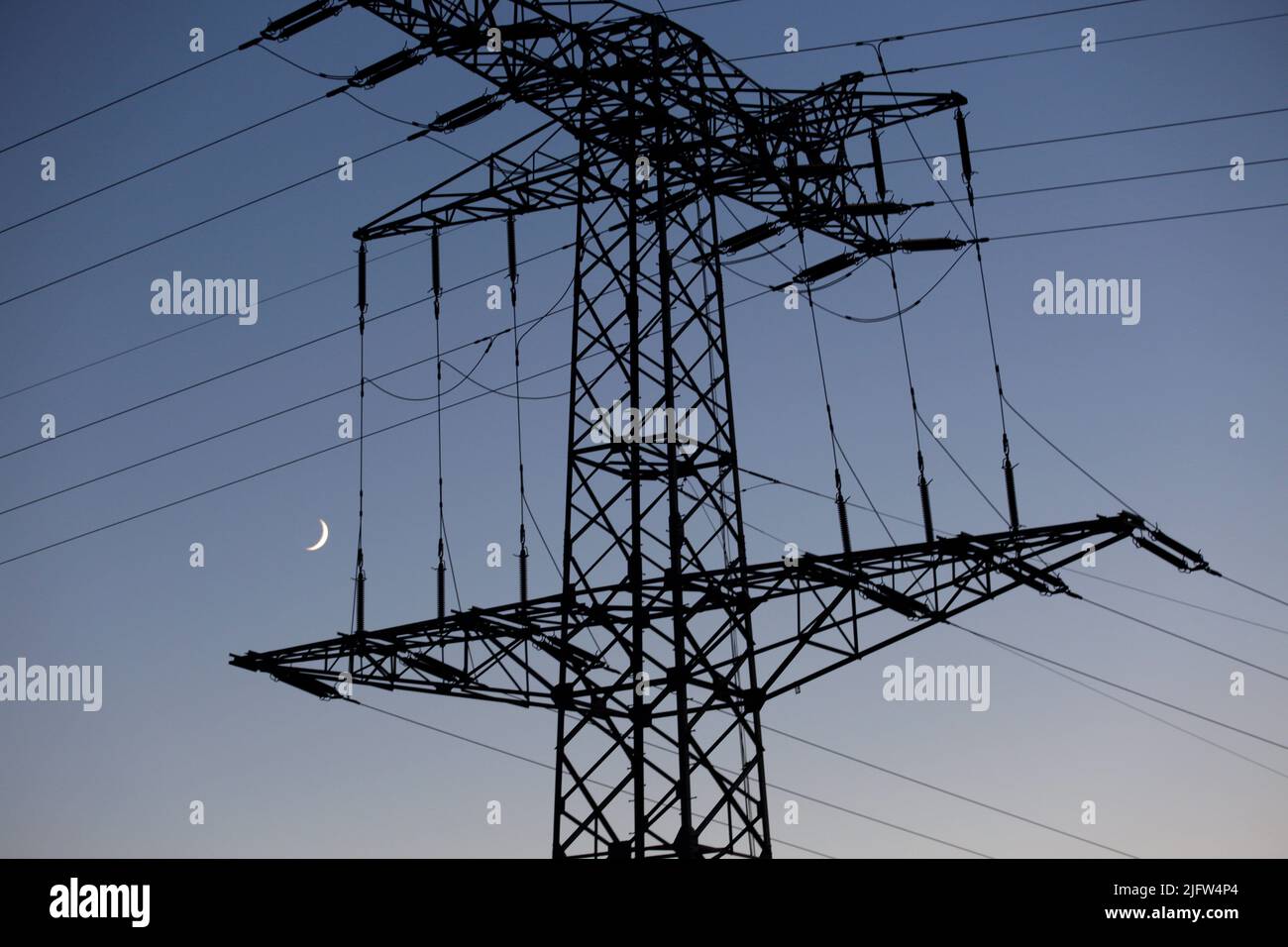 Kemberg, Germany. 02nd July, 2022. Behind a power pole the crescent moon can be seen in the evening. Credit: Viola Lopes/dpa/Alamy Live News Stock Photo