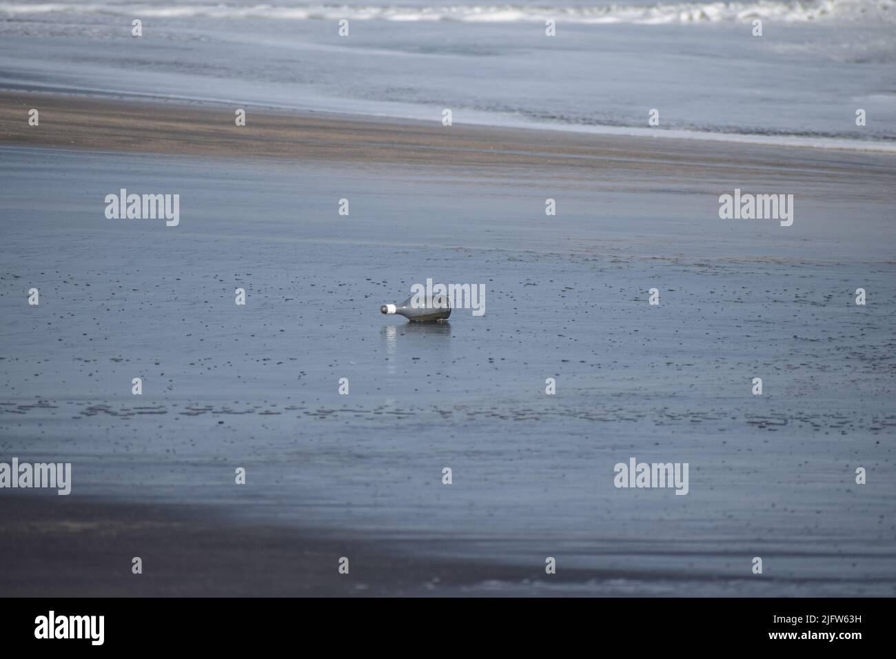 Discarded glass bottle lying on a seashore Stock Photo
