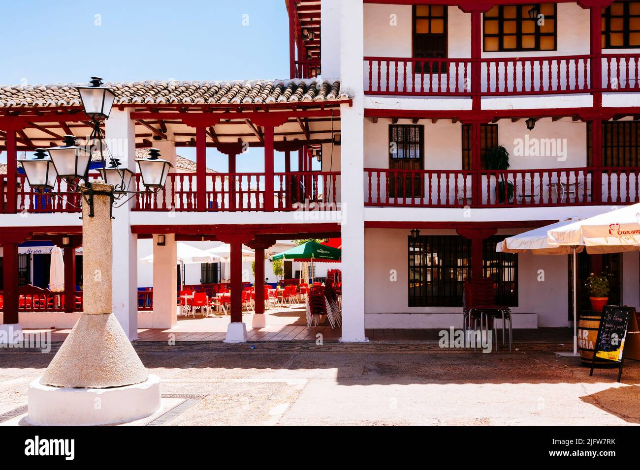 The Plaza de la Constitución, Plaza Mayor, in Puerto Lápice is a La Mancha-style square, with two levels of wooden arcades painted red. Puerto Lápice, Stock Photo