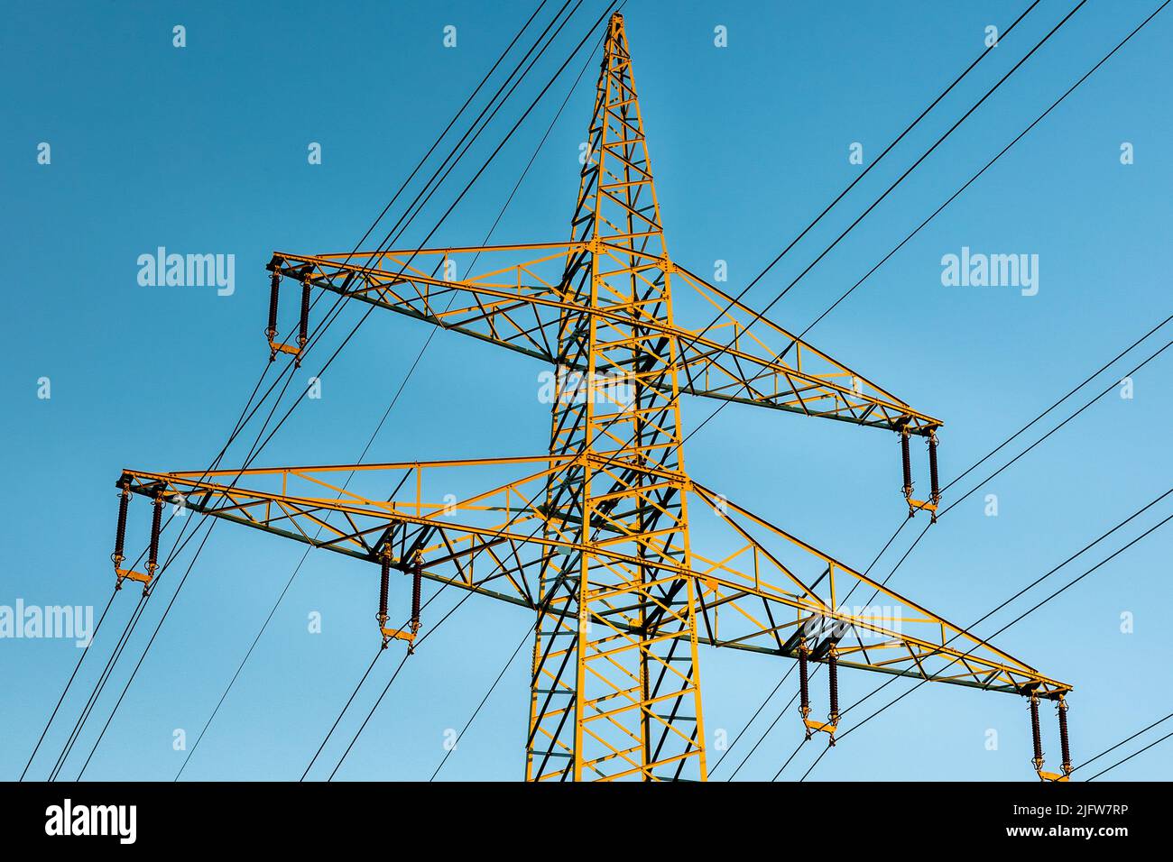 High voltage power line tower on a panorama of blue sky, taken at sunset. Stock Photo