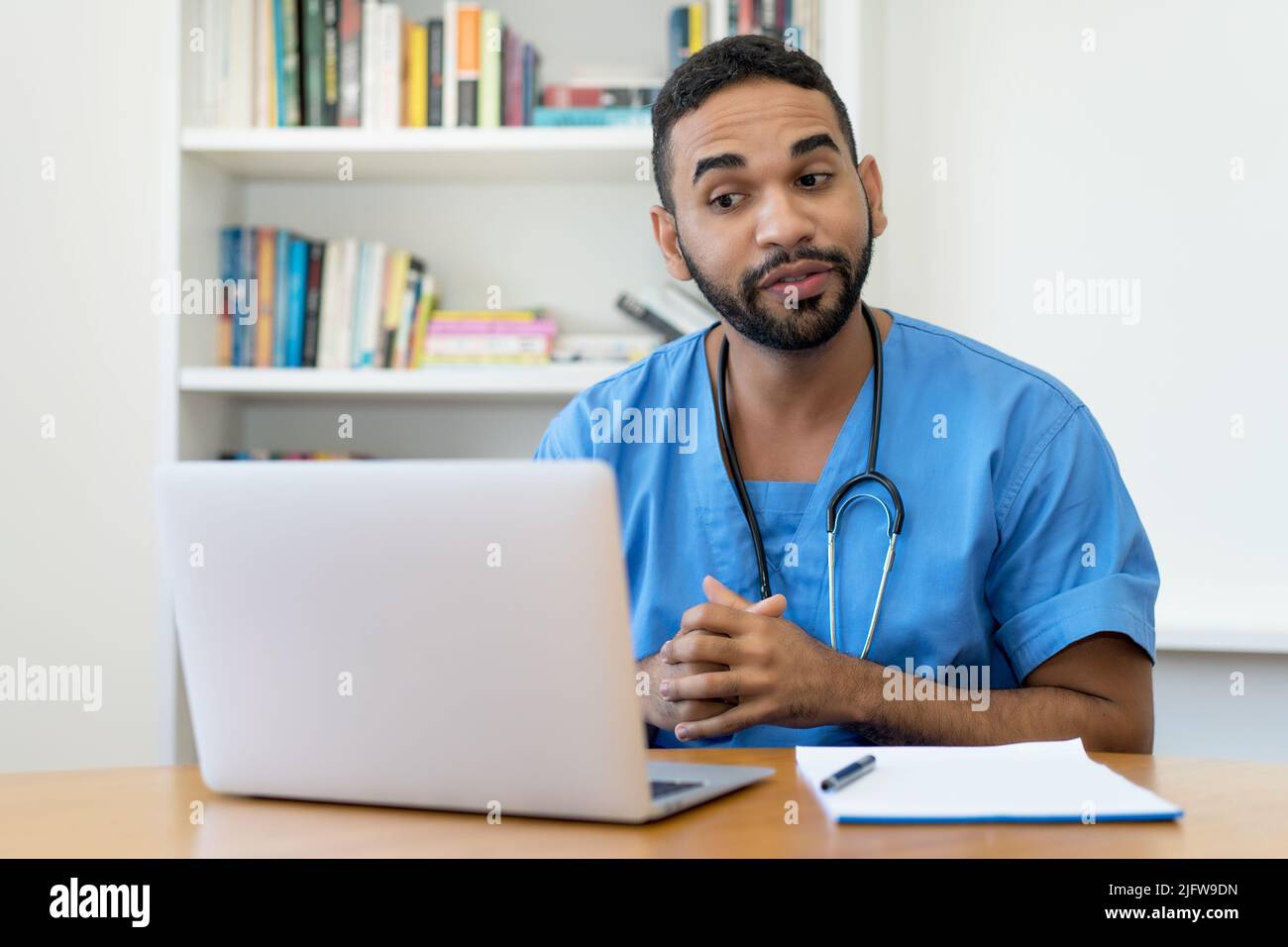 Handsome latin american male nurse talking with patient at computer at hospital Stock Photo
