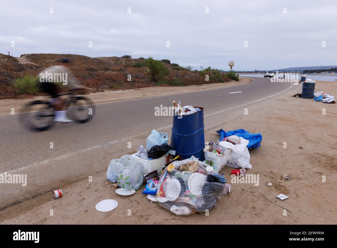 A cyclist rides past trash left behind following the Fourth of July holiday on Fiesta Island in San Diego, California, U.S. July 5, 2022. REUTERS/Mike Blake Stock Photo