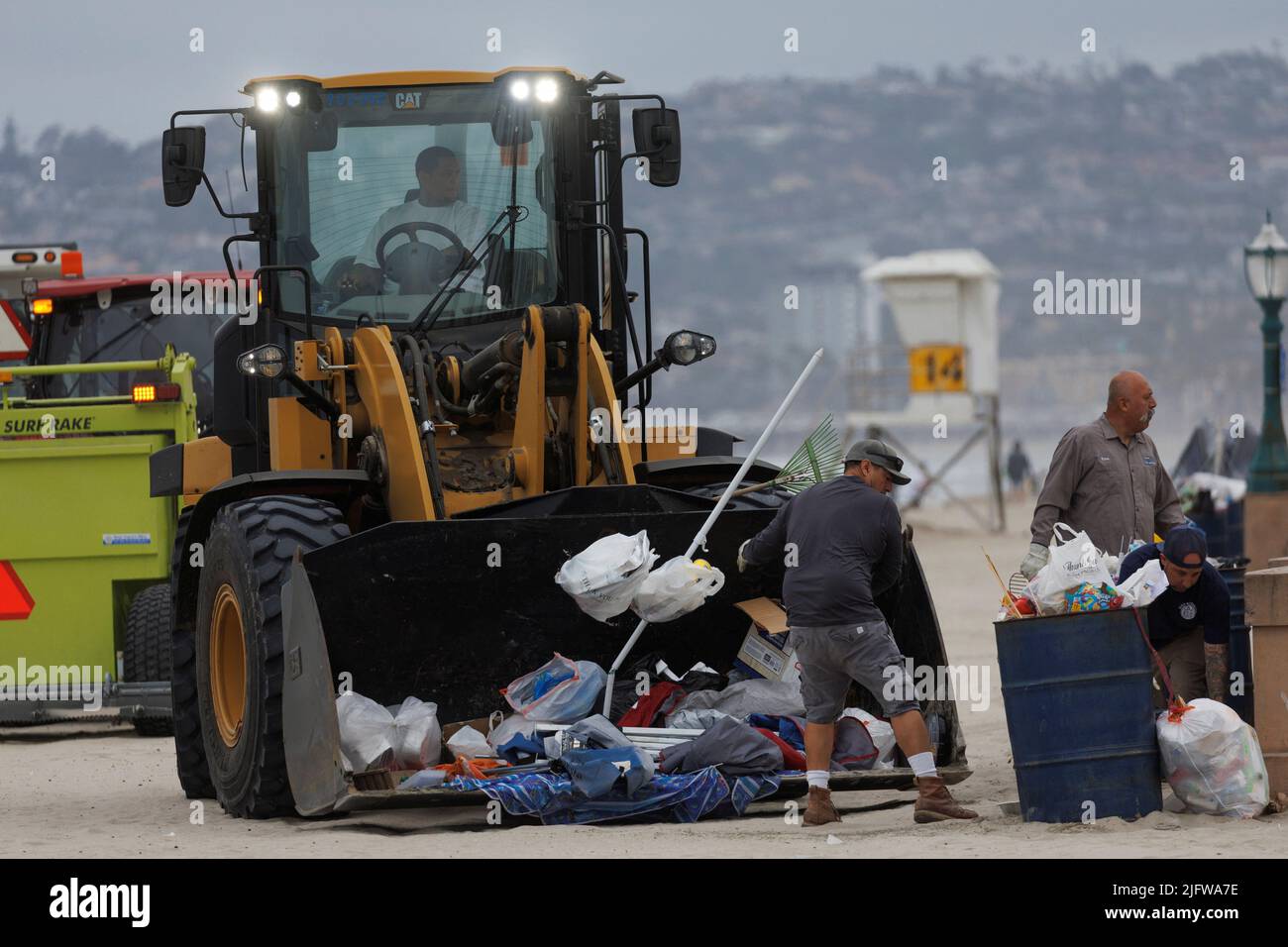 City workers use a front-end loader to pick up trash following the Fourth of July holiday at Pacific Beach in San Diego, California, U.S. July 5, 2022. REUTERS/Mike Blake Stock Photo