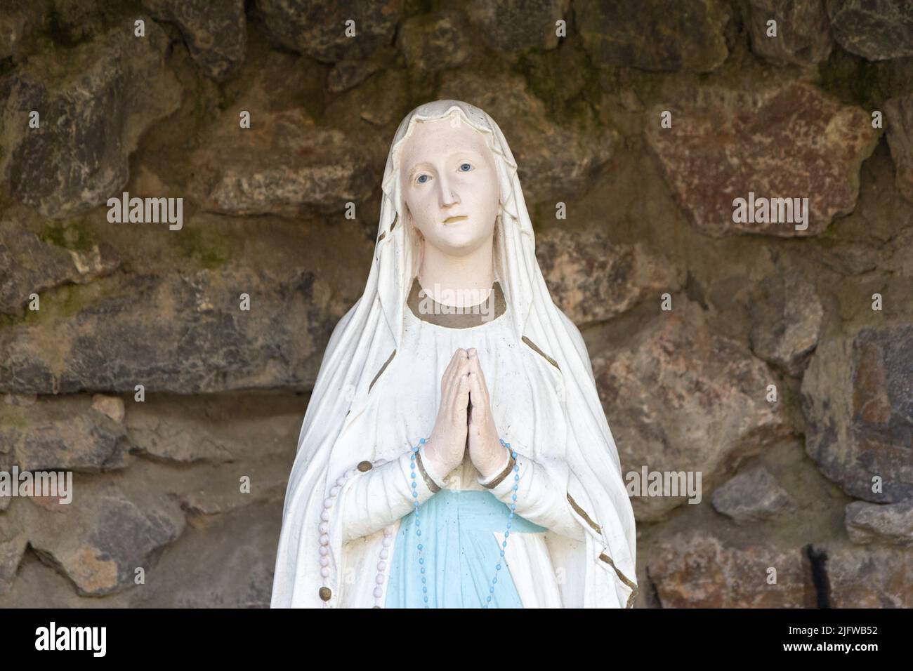 The statue of Our Lady of Lourdes (Notre Dame de Lourdes) in a grotto in a garden in Valenciennes, France. Stock Photo