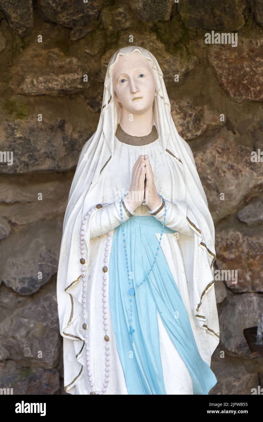 The statue of Our Lady of Lourdes (Notre Dame de Lourdes) in a grotto in a garden in Valenciennes, France. Stock Photo