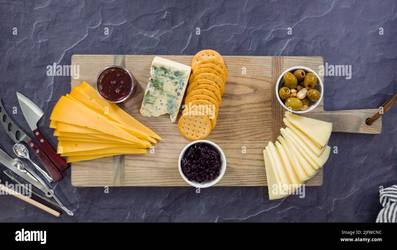 Flat lay. Arranging gourmet cheese, crakers, and fruits on a board for