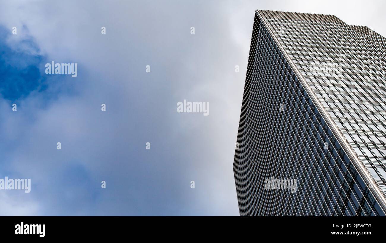 Abstract Architecture. Low angle view of a generic skyscraper in London's business district, Docklands, set against sky and clouds copy space. Stock Photo