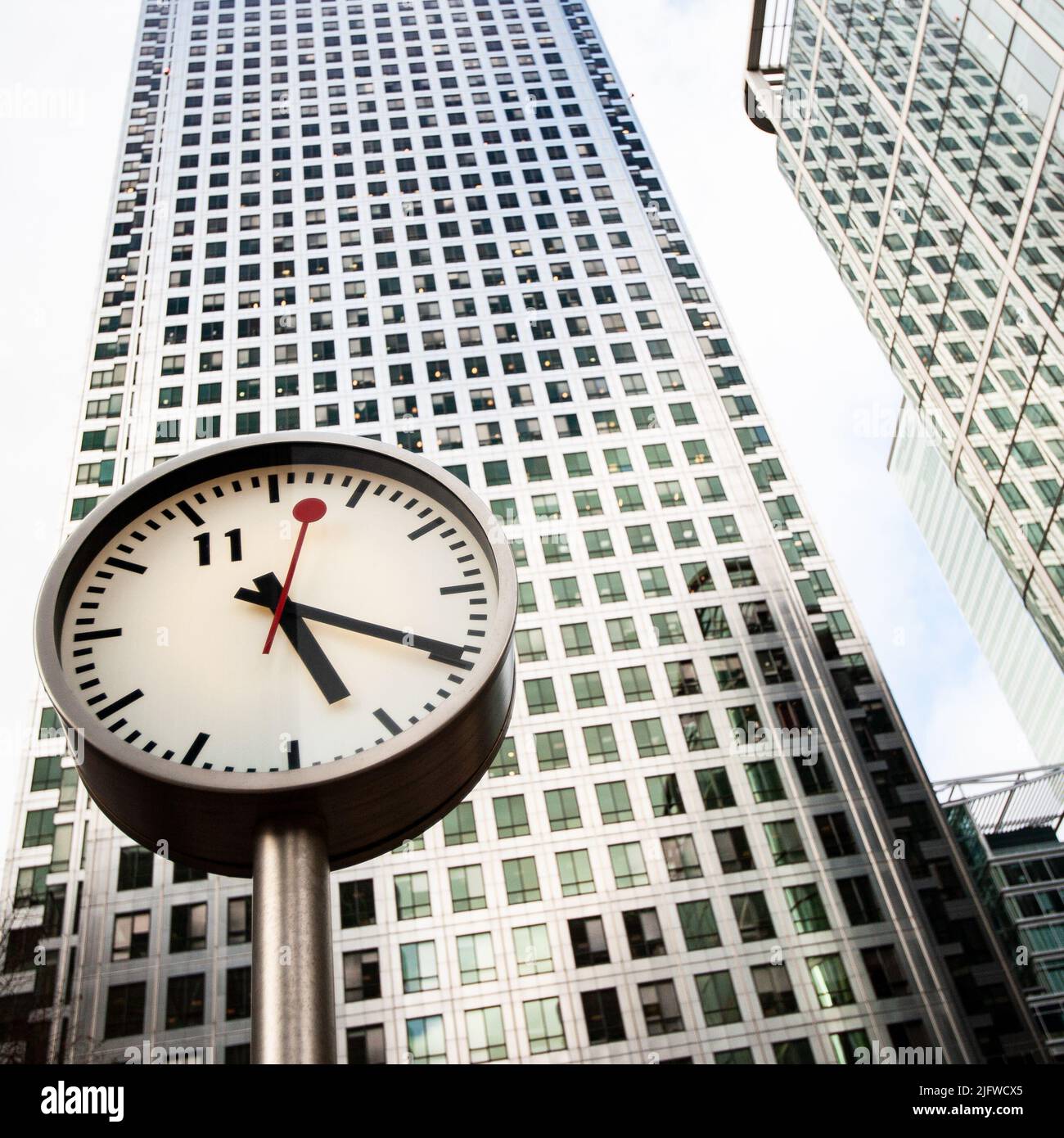 Docklands Clocks, London, UK. A low, wide angle view of Canary Wharf tower fronted by one of Konstantin Grcic's Six Public Clocks sculpture. Stock Photo