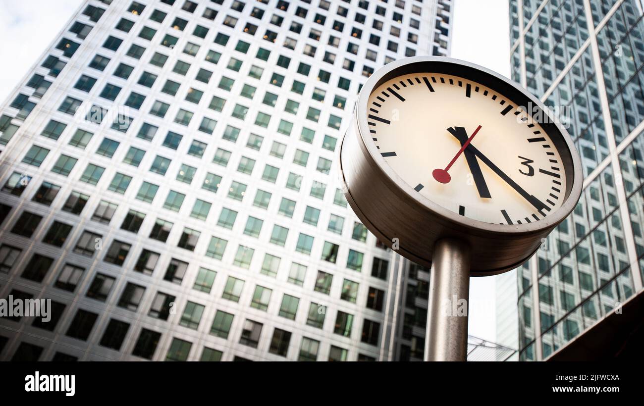 Docklands Clocks, London, UK. A low, wide angle view of Canary Wharf tower fronted by one of Konstantin Grcic's Six Public Clocks sculpture. Stock Photo